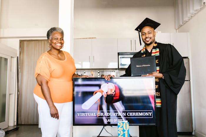 A joyful virtual graduation ceremony featuring a proud graduate and family member indoors.