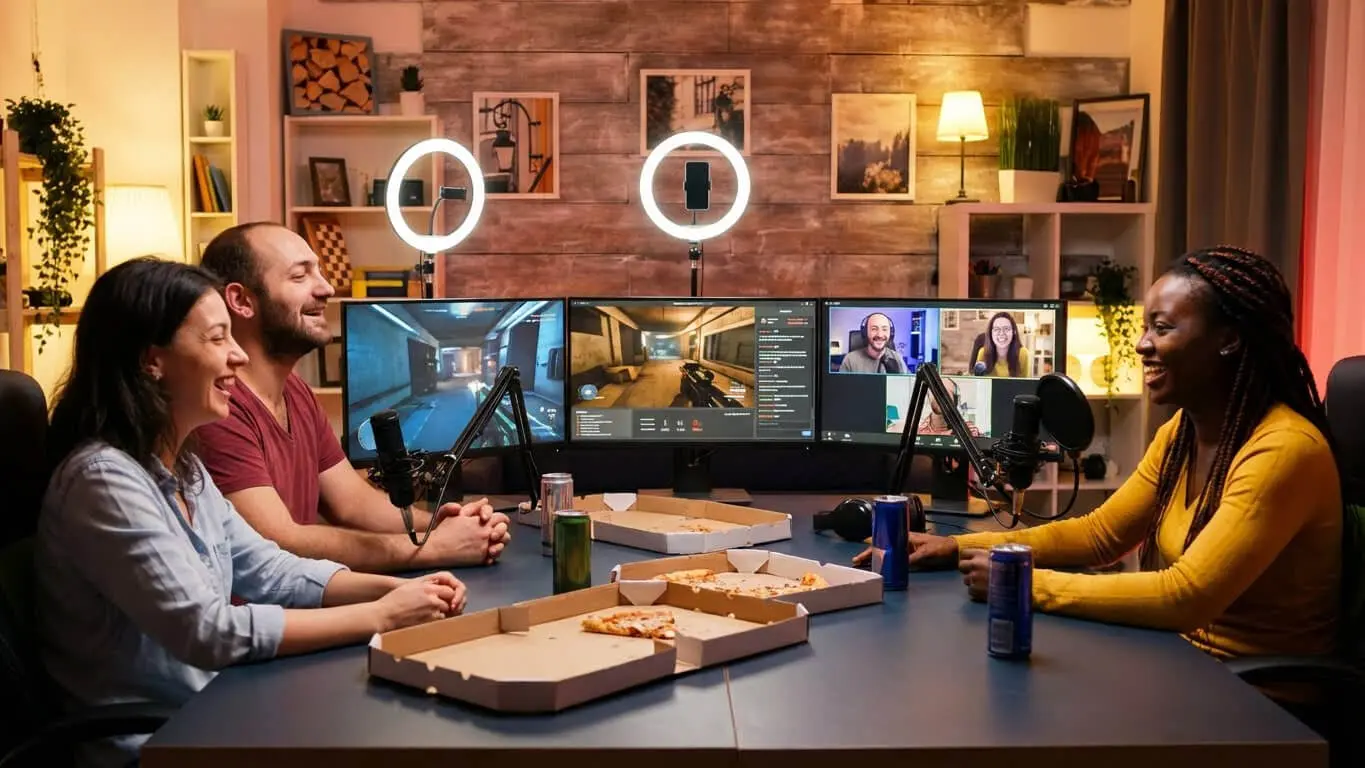 Three people sit at a table with pizza and drinks, recording a podcast or livestream for their Twitch channel in a studio filled with microphones, computers, and ring lights. Uploaded on aifreeforever.com