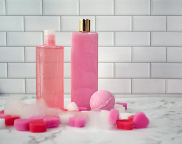 Elegant display of pink bath products on a marble surface with a tiled backdrop.