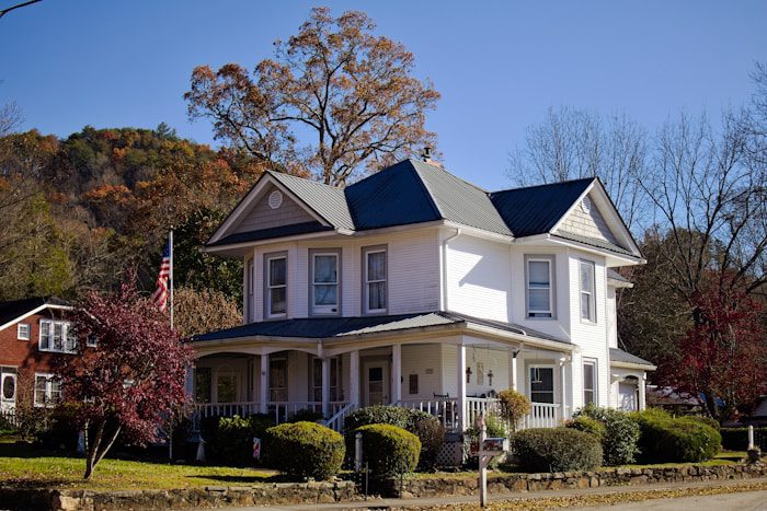 A white two-story house with a wraparound porch.