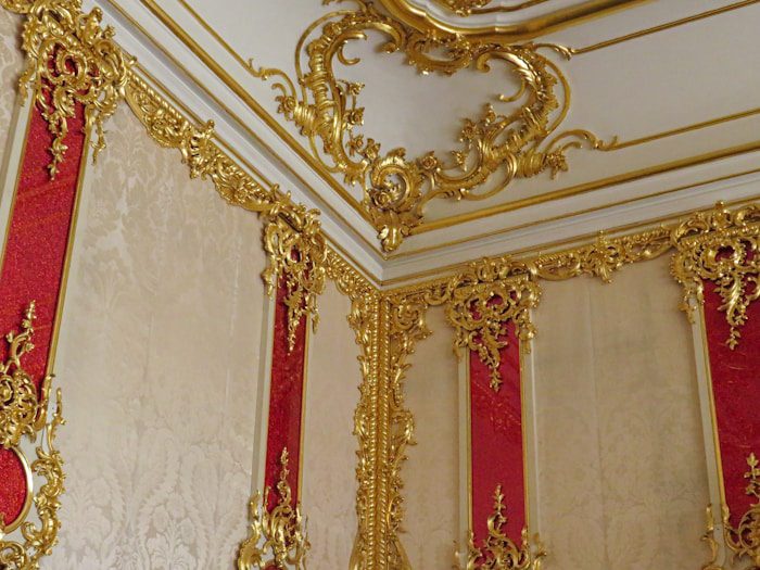 a gold and red room with a clock on the wall
