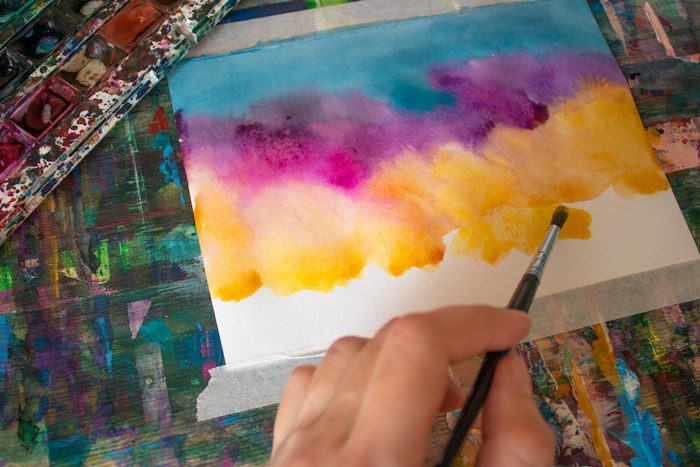 a person is painting on a piece of paper