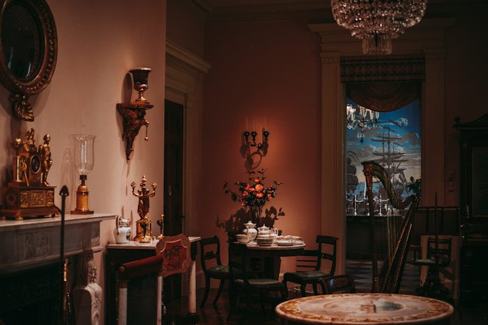 Antique dining room with ornate chandelier and wallpaper.